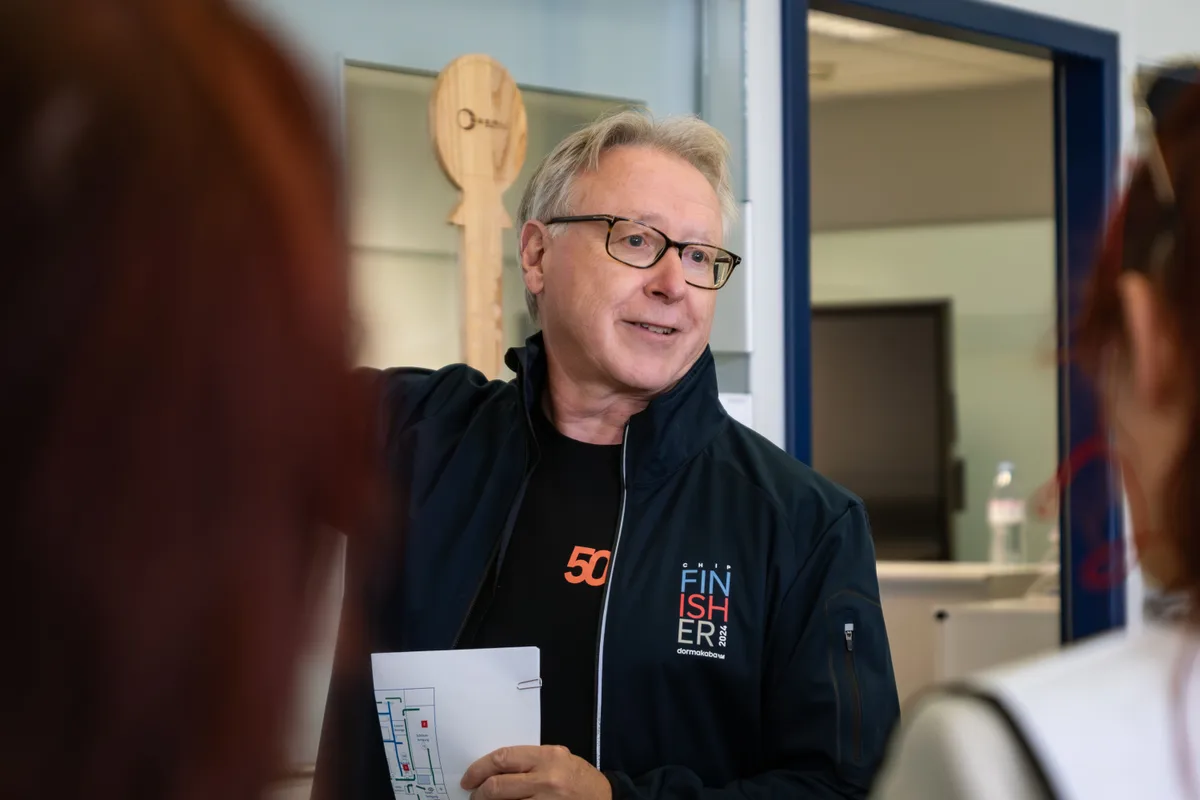 Christoph Kunz ist Leiter des Produktionsstandorts Wetzikon. Er kennt die Hallen und Abläufe wie seine Hosentasche. Man sieht einen Mann, der etwas erklärt.